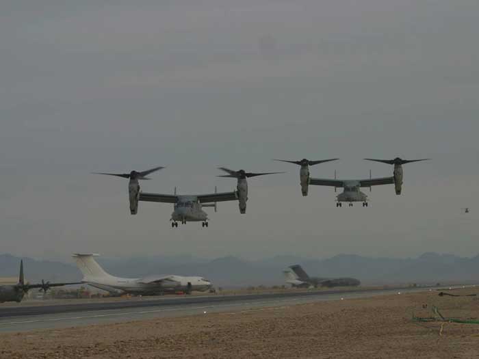 a group of airplanes flying over a runway